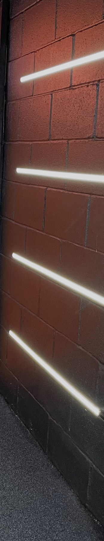 Charcoal brick wall with angled LED light strips in the studio entrance tunnel